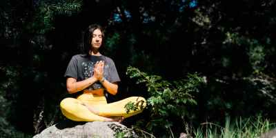 photo of woman doing yoga while sitting on rock