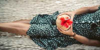 woman in green and white polka dot dress lying on a hammock with fresh coconut juice