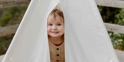 happy little child smiling while peeking from tent