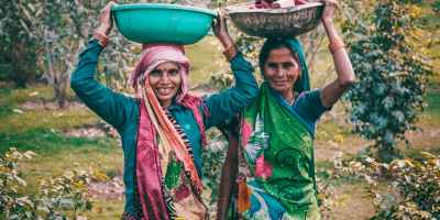 two women wearing traditional dress carrying basins