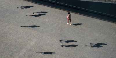 girl in pink shirt and black pants walking on gray concrete pathway