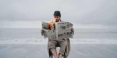 man holding a burning newspaper