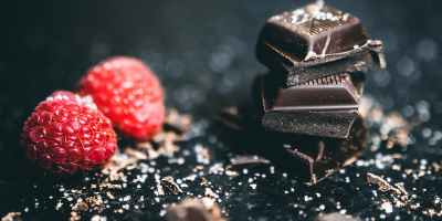 close up photo of stacked chocolates bars beside raspberries