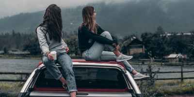 two women sitting on vehicle roofs