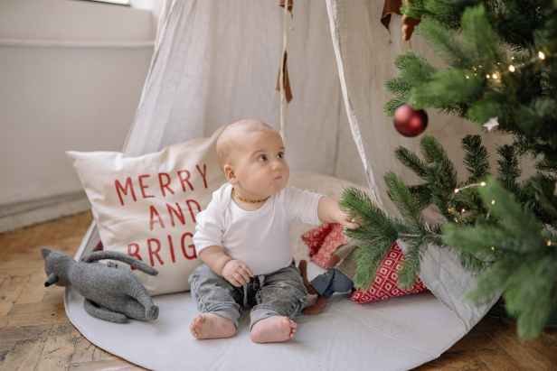 baby sitting beside the christmas tree
